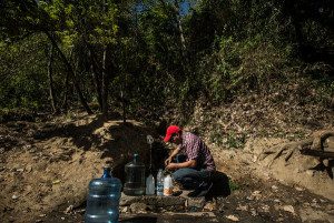 Fernando Zambrano, 31, filled jugs of water trickling down from Mount Avila. Credit Meridith Kohut for The New York Times